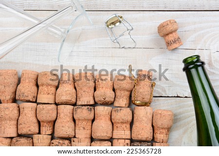 HIgh angle shot of a empty champagne bottle with corks and two flutes. Closeup on a rustic white wood table. Horizontal format.