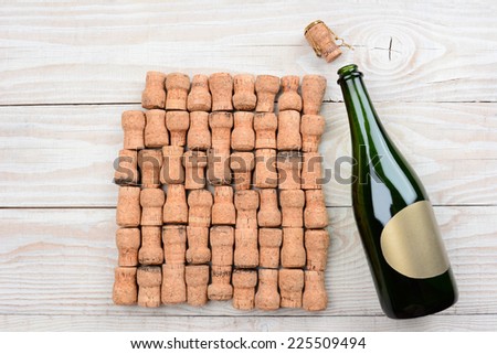 HIgh angle shot of a empty champagne bottle with blank label and corks. Closeup on a rustic white wood table. Horizontal format with copy space.