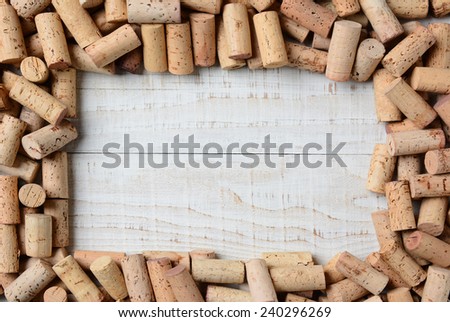 Overhead shot of a group of wine corks forming a frame on a rustic whitewashed wood table. Horizontal format.