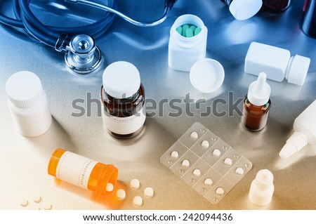 Medicine bottles pills and stethoscope on a stainless steel surface with reflections of different colors. Horizontal format.