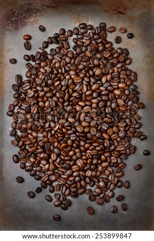 High angle shot of fresh roasted coffee beans ion a metal baking sheet. Vertical format.