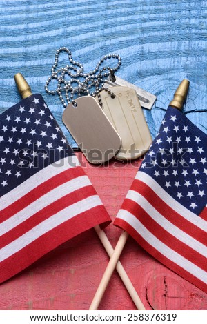 Overhead shot of a set of dog tags and two American flags on a red white blue patriotic table. Vertical format. Useful for 4th of July, Memorial Day and Veterans Day projects.