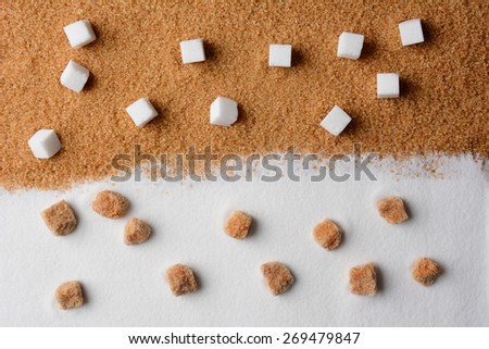 White and brown sugar contrast. White sugar cubes on raw brown turbinado granules and raw brown sugar lumps on white granulated sugar.