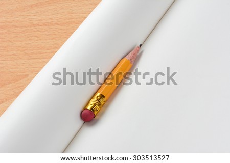 Closeup view of a pencil stub resting on blank notebook. horizontal format at an angle with copy space.