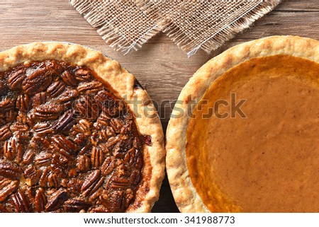 Closeup of two pies on a Thanksgiving holiday table. Pumpkin and pecan pies are traditional desserts for the American holiday.