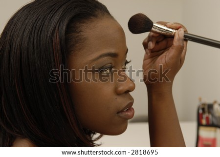 Attractive African-American woman using brush to apply powder