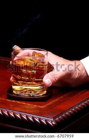 Mans Hand Holding Whiskey Glass and Cigar on wood & Leather Table Top