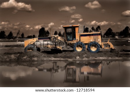 Earth Mover with reflections in water - sepia toned