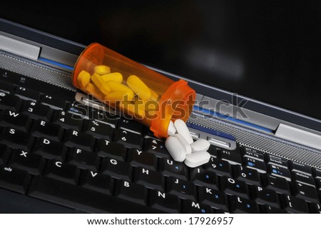 Pills Spilling from Prescription Bottle on Laptop Computer Keyboard