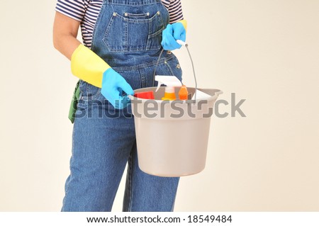 Woman in overalls holding a bucket full of cleaning supplies.