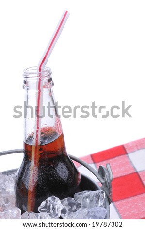 Soda bottle in bucket of ice on checkered table cloth isolated on white
