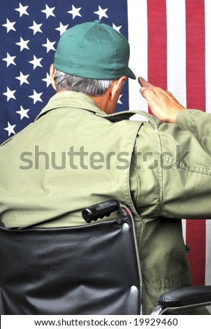 American veteran in wheelchair and fatigues saluting flag