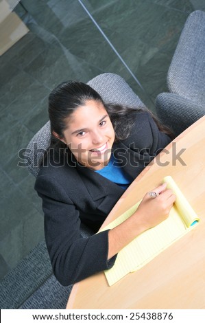 Smiling officeworker taking notes at a conference table seen from above