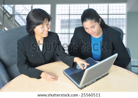 Two Business Women in Office Setting Using Laptop