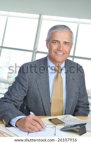 Smiling Middle Aged Businessman at desk in Modern Office Building