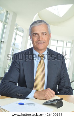 Middle Aged Businessman Seated at His Desk in Modern Office Setting