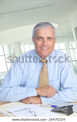 Middle Aged Businessman Seated at His Desk in Modern Office Setting