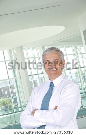 Middle Aged Businessman Wearing White Shirt and Tie with Arms Folded in Office Setting