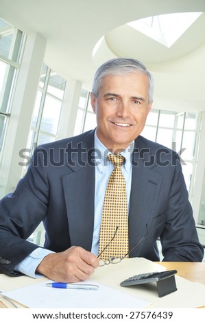 Smiling Middle Aged Businessman Seated at Desk in office setting