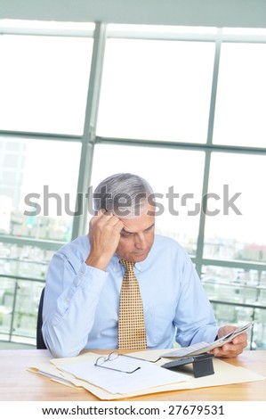 Middle Aged Businessman Reading Newspaper at His Desk in Office Setting