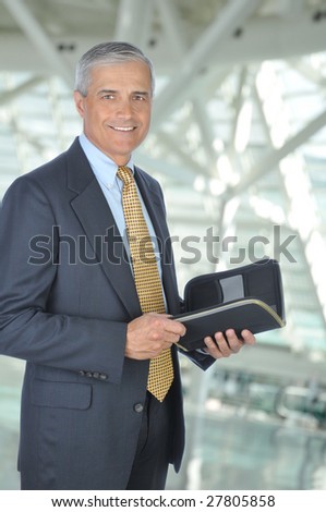 Standing Middle Aged Businessman with Planner Notebook in Office Setting