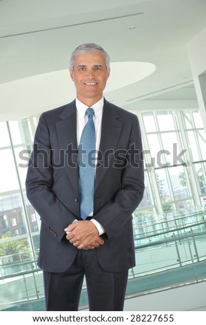 Standing mature Businessman with hands in front in office setting