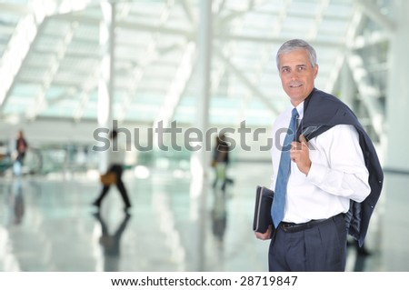 Middle Aged Business Traveler in Airport Concourse with blurred travelers in background