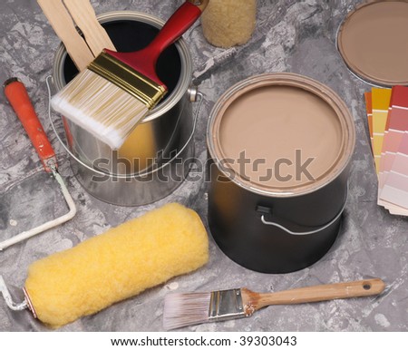 Painting supplies arranged on a drop cloth, with open paint can, roller and brushes.