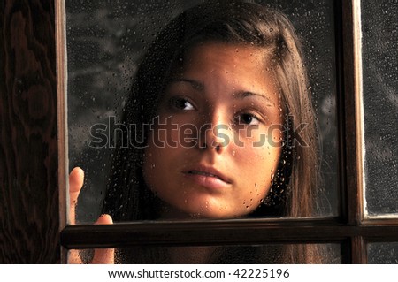 Pretty Teenage Girl in Window with Rain Drops and sad expression on her face