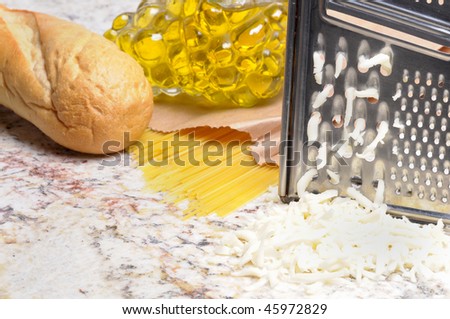 Preparations and ingredients for an Italian dinner bread, pasta, cheese, olive oil horizontal format shallow DOF