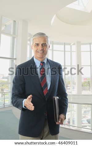 Middle Aged Businessman in Blue Blazer and Khaki Trousers with hand extended to shake vertical format