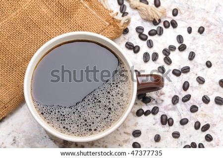 Overhead view of a Large Coffee Mug on Granite Countertop with spilled coffee Beans horizontal format