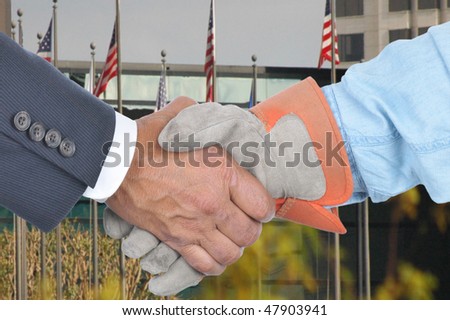Businessman and laborer wearing a work glove handshake in front of a building with flags. Management and Labor negotiation concept. Hands and sleeves only in horizontal format.