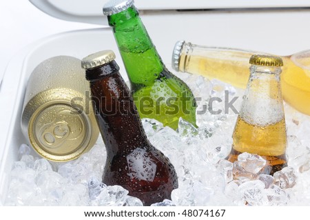 Close up of an assortment of beer bottles and cans in cooler with ice horizontal composition