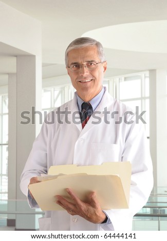 Middle aged male doctor in lab coat holding a manila folder in modern medical office setting.