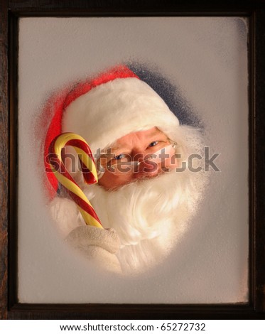 Santa Claus seen through a frosted window holding up a large candy cane.