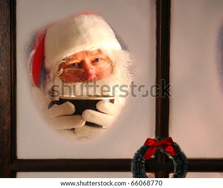 Santa Claus seen through a frosted window holding a large mug of cocoa. Horizontal format.