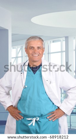 Close up portrait of a smiling middle aged doctor in scrubs with stethoscope around his neck. Vertical format in modern medical facility.