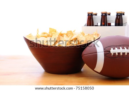 Chips, football and Six Pack of Beer on a table with a white background. Horizontal format. Great for Bowl Game projects.