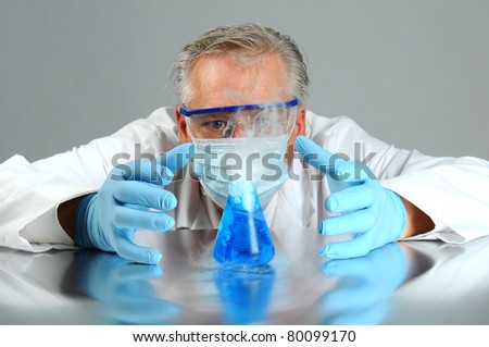 Closeup of a mad scientist as he observes his experiment. Man is hidden behind a glass beaker that is bubbling over and smoking.