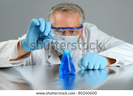 Closeup of a mad scientist pouring a liquid from a test tube into a beaker that is emitting smoke. Horizontal format.