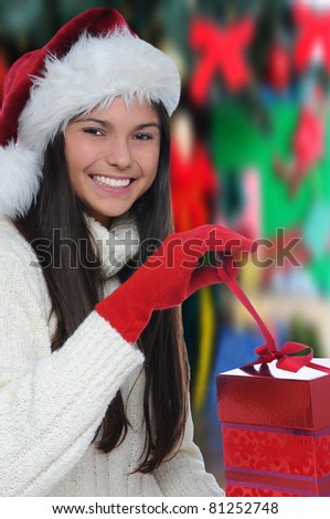 Attractive smiling young woman opening a Christmas Present. Vertical format with out of focus background.