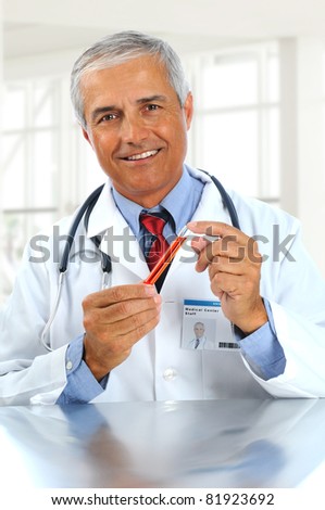 Doctor holding as test tube with red liquid in modern medical facility. Man is wearing a lab coat, blue shirt and tie and stethoscope. Vertical format.