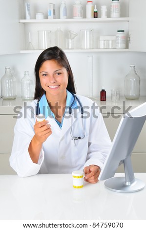 Young female pharmacist holding a prescription with computer in pharmacy setting. Vertical format.