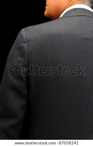Closeup of a middle aged businessman looking over his shoulder. Seen from behind on a black background
