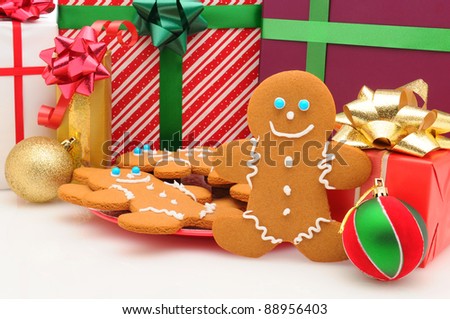 A plate of Ginger Bread Man cookies in front of Christmas presents. Horizontal format.