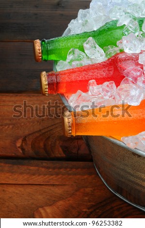 Soda Bottles in a metal party bucket on a picnic table. Overhead view in vertical format.