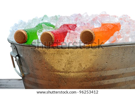 Closeup of assorted soda bottles in a metal party bucket filled with ice.