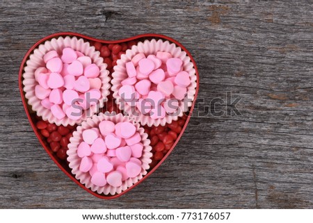 Top view of a heart shape tin with Valentines Day Pink Candy Hearts on a rustic wood table.
