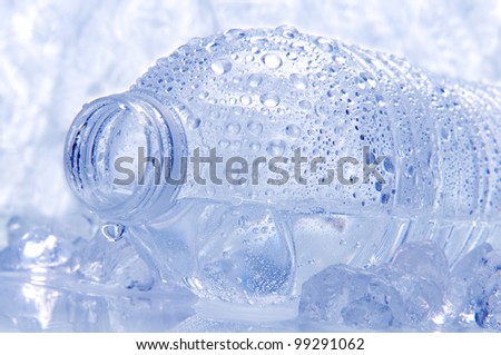 Closeup of a water bottle laying on its side with droplets and drip coming out of the opening. Intentional cool tones and shallow depth of field